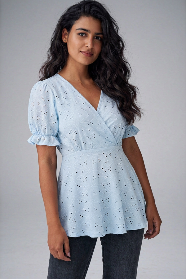 Model wearing a light blue eyelet peplum wrap blouse with short puff sleeves and v-neckline.